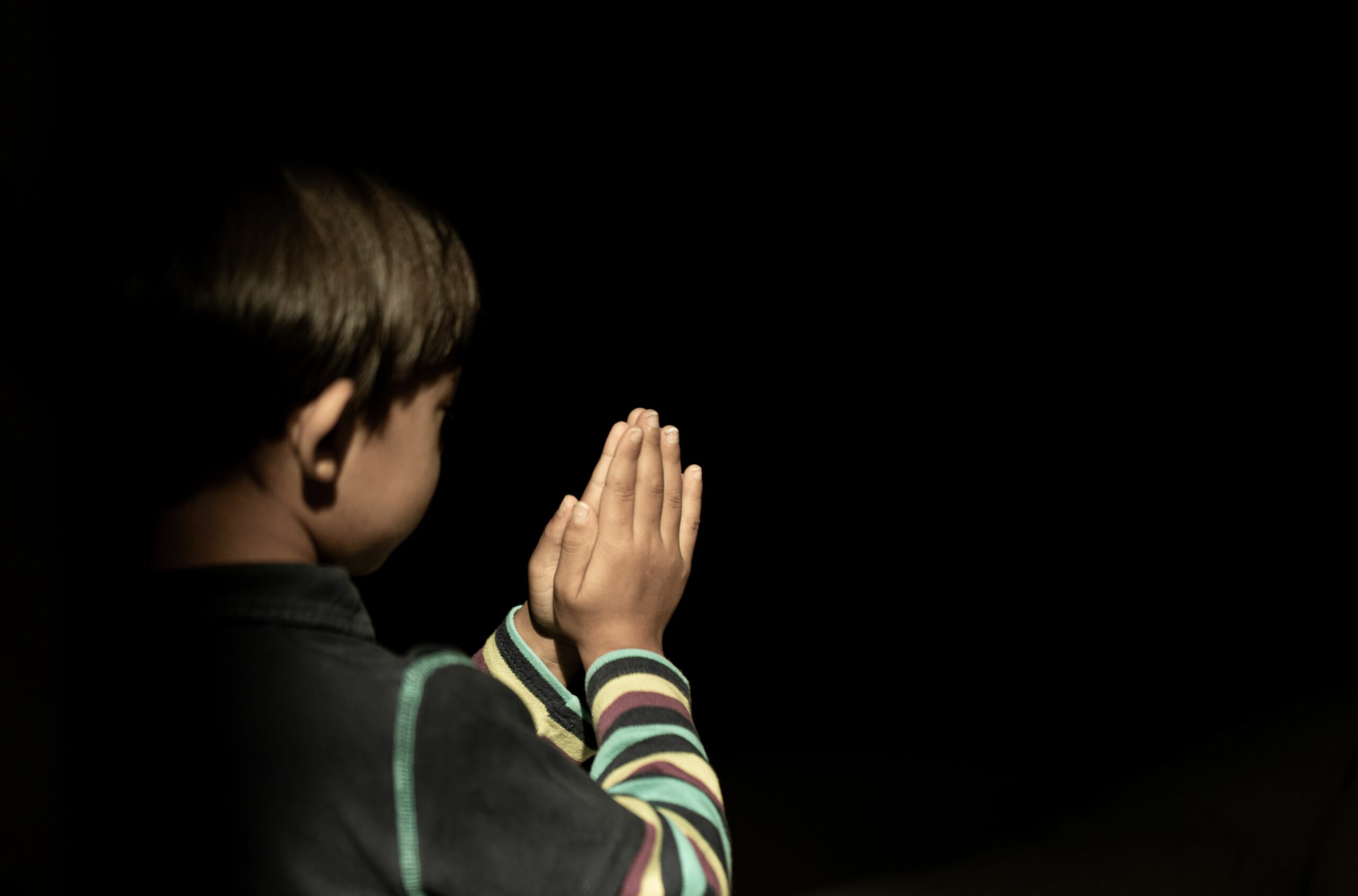 Little Boy Praying God Dark Background